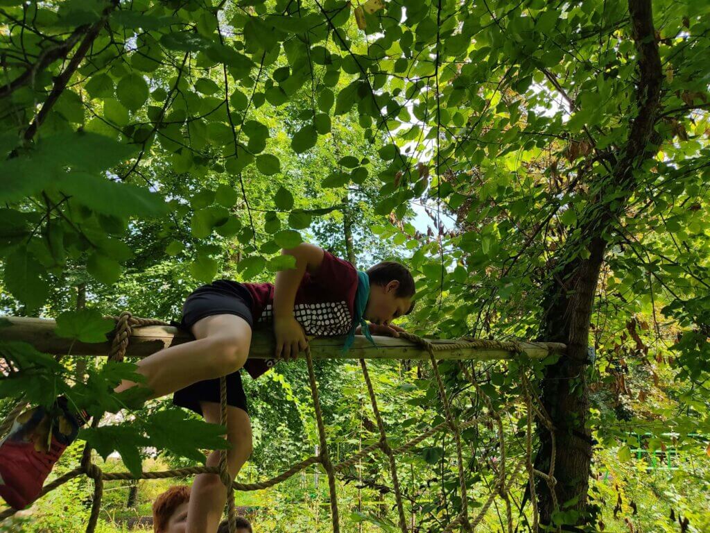 Jongen klimt over obstakel in bos